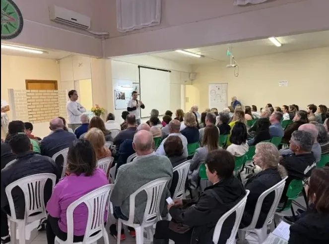 Público sentado em um salão durante a Caravana em Caxias do Sul, RS